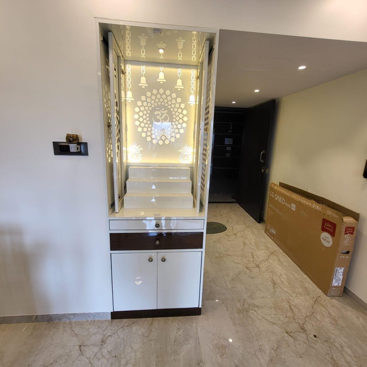 Custom white pooja unit with illuminated jali panels in an apartment foyer